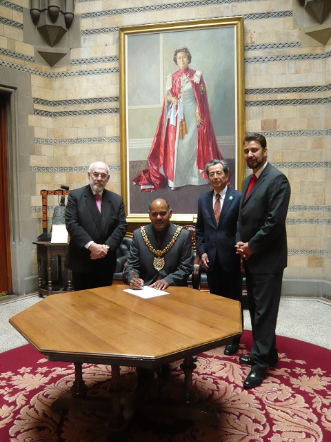 リーダー都市就任承諾書にサインするハッサン市長（イギリス・マンチェスター市）